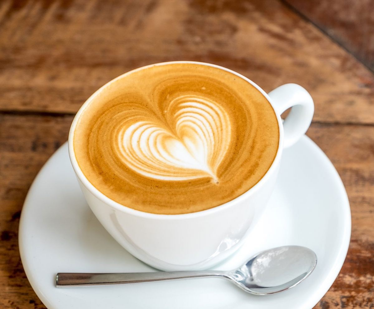 Fresh latte with heart-shaped latte art on a wooden table